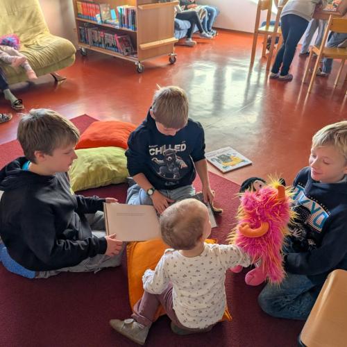 Schüler sehen gemeinsam mit Dorfknirps Buch an