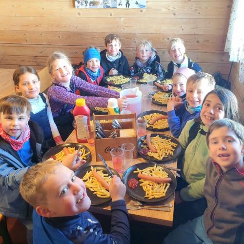 Kinder beim Einkehrschwung mit Würstel und Pommes