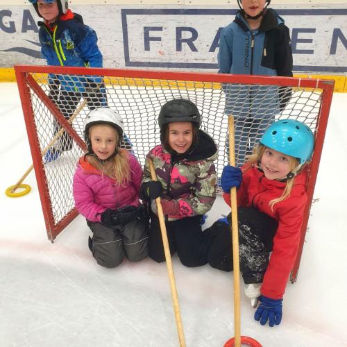 Kinder sitzen im Eishockey-Tor