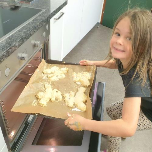 Mädchen schiebt Blech mit Osterbroten in den Ofen