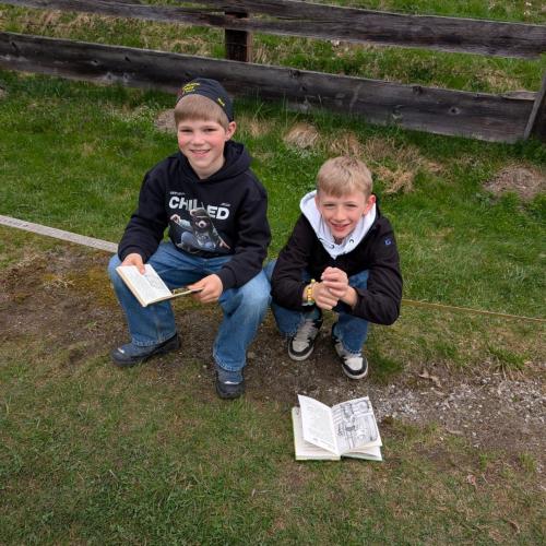 2 Buben beim Lesen im Gras