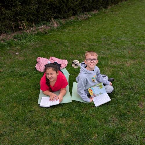2 Kinder liegen im Gras beim Lesen