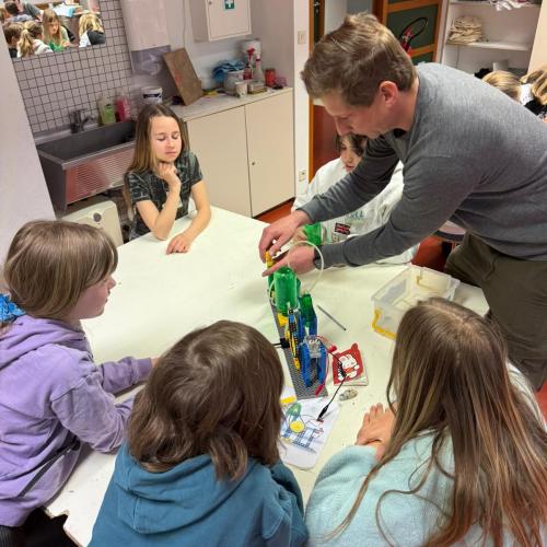 Kinder sitzen beim Workshop um Tisch