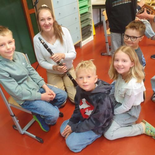 Gruppe von Kindern um Frau mit Klarinette herum