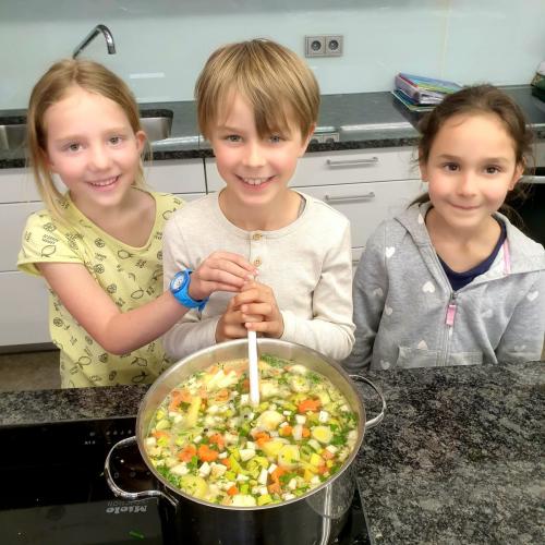 Kinder vor Gemüsesuppentopf