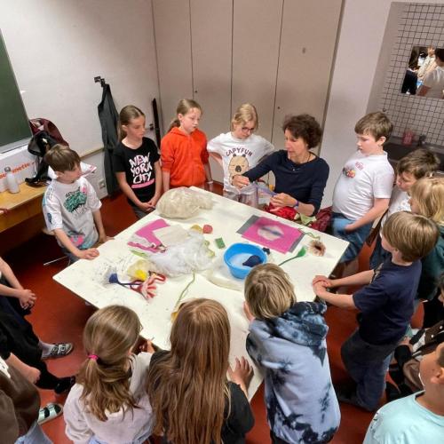 Kinder sitzen um den Tisch beim Filzen