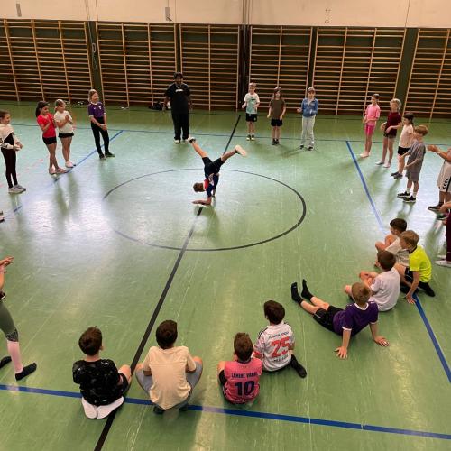 Kinder im Kreis um Lehrer, der Move vorzeigt