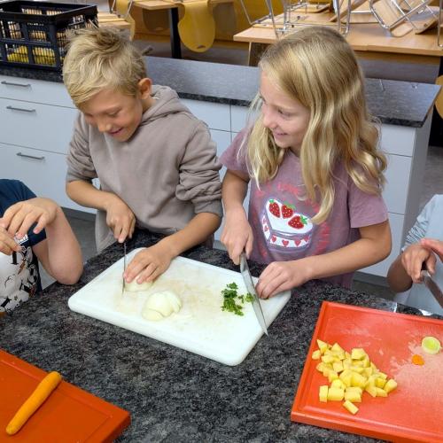 Kinder beim Schneiden des Gemüses für die Bohnensuppe