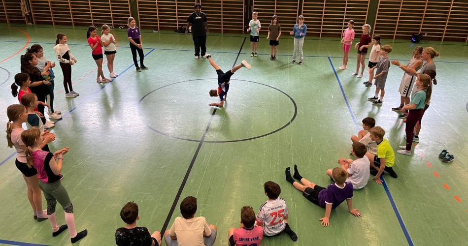 Kinder im Kreis um Lehrer, der Move vorzeigt